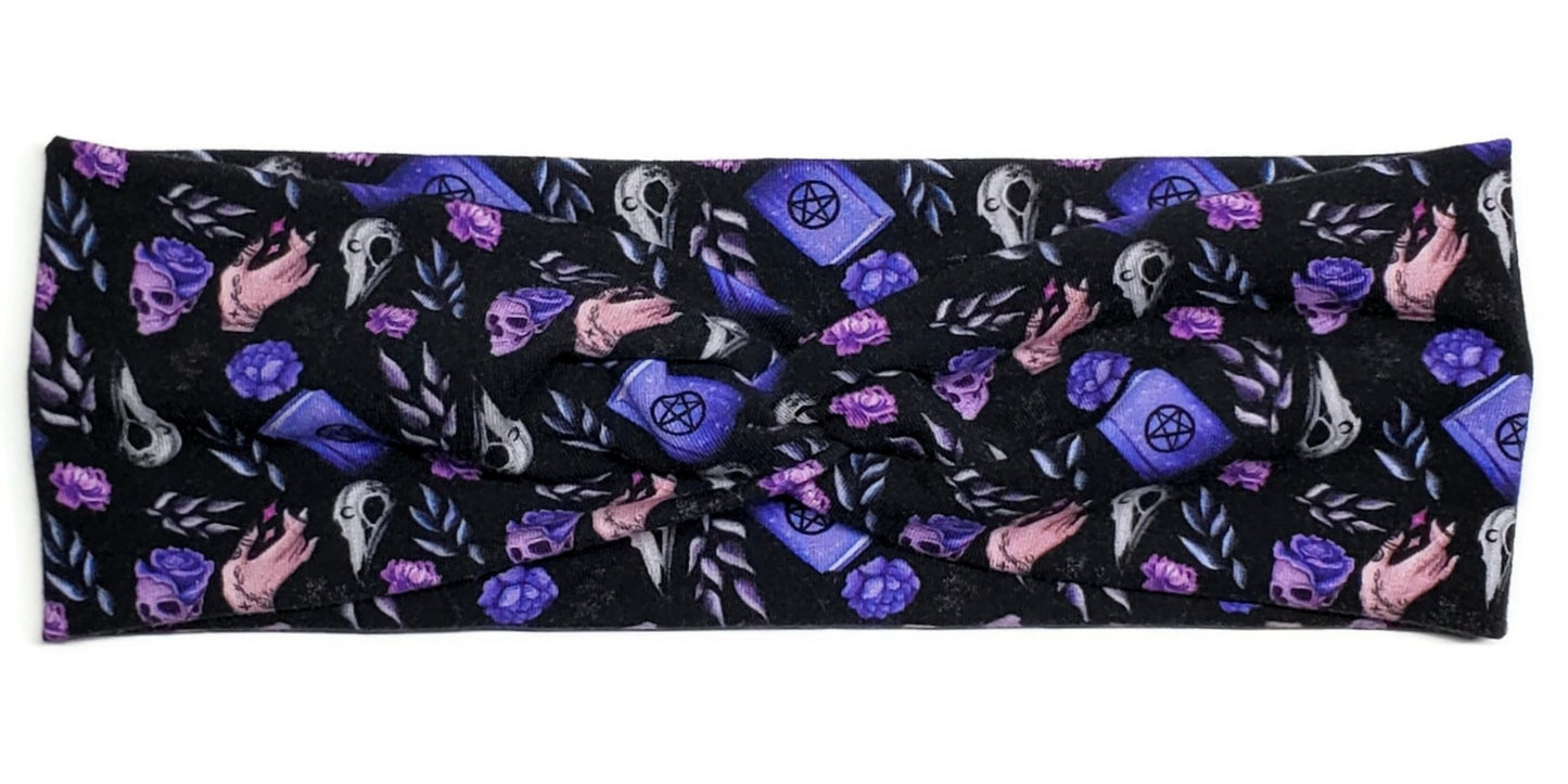 Witchy purple spell books, raven heads and flowers on a black twist headwrap headband for women